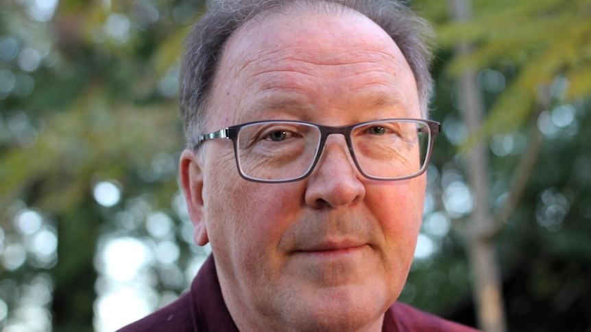 A man wearing glasses and a maroon shirt.