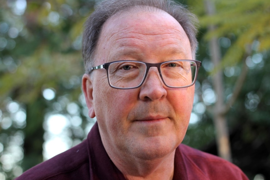 A man wearing glasses and a maroon shirt.