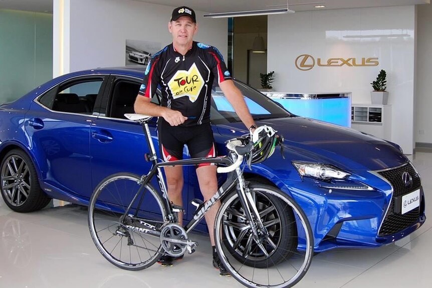 A man next to a bike and car