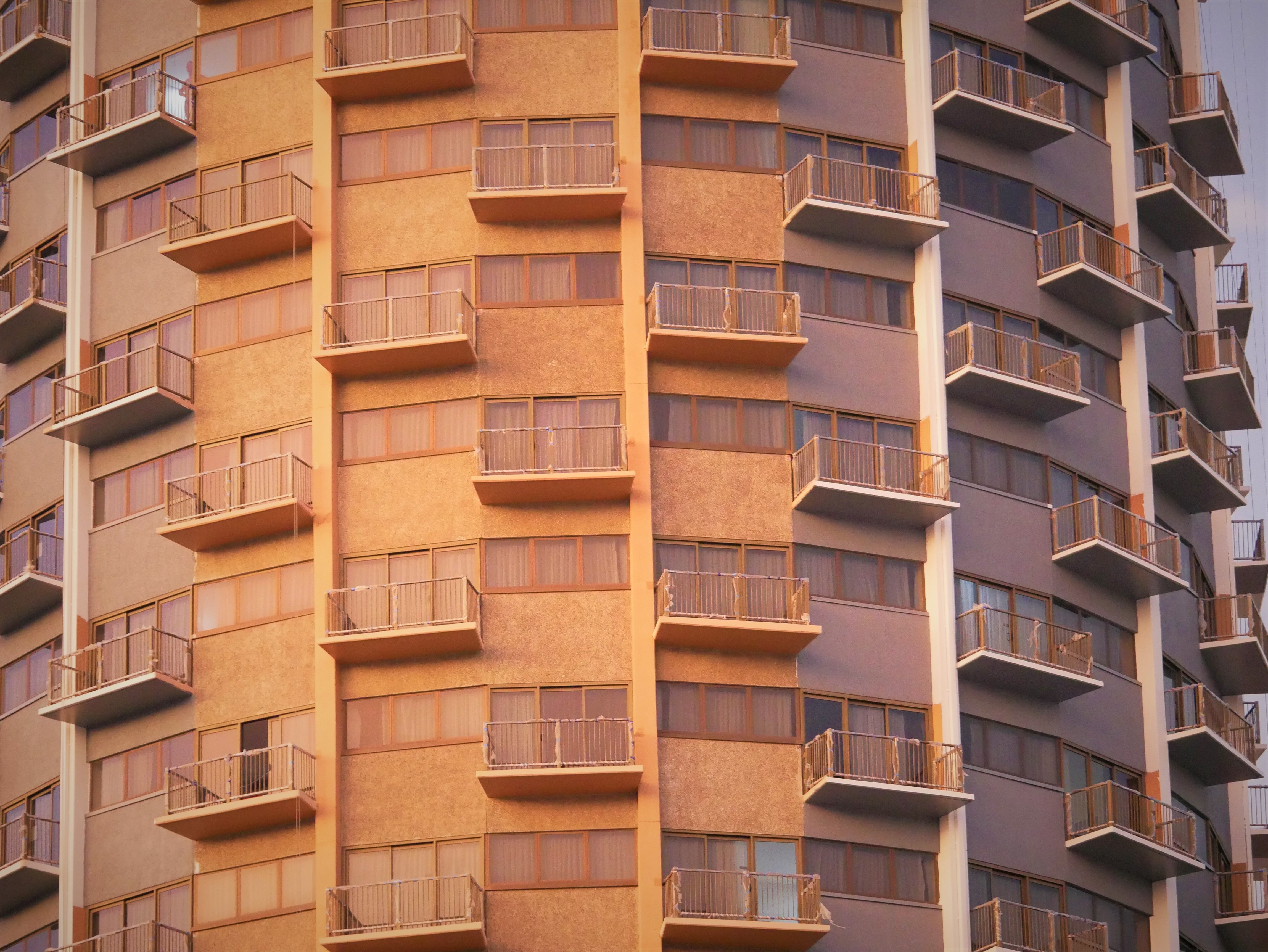 A photo of several balconies on a sandstone building.  Half of them have been painted gray and white. 