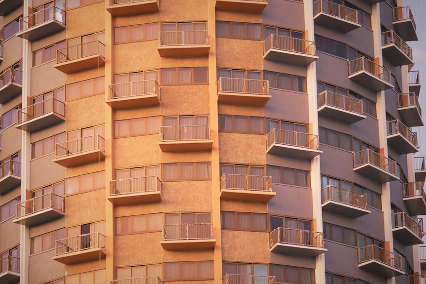 A photo of several balconies on a sandstone building.  Half of them have been painted gray and white. 