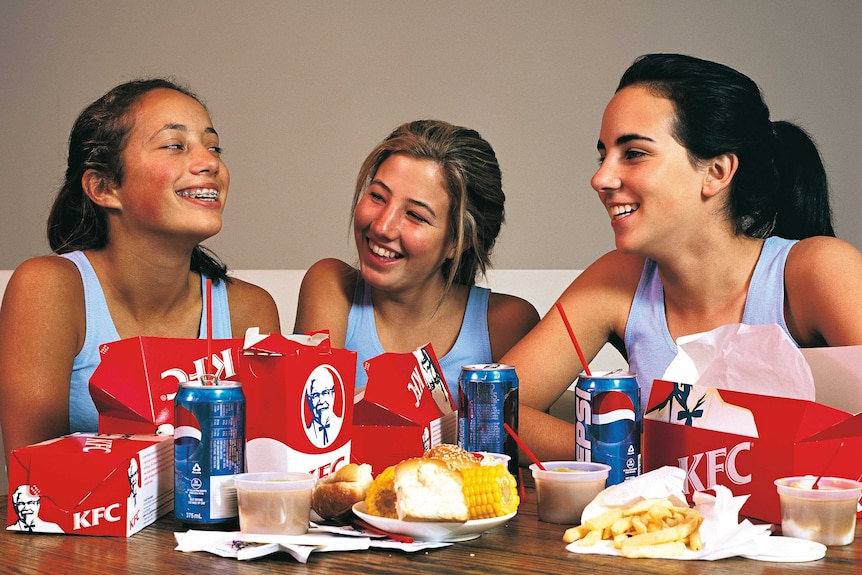 A photograph by the artist Darren Sylvester of three teenage girls with boxes of KFC in front of them