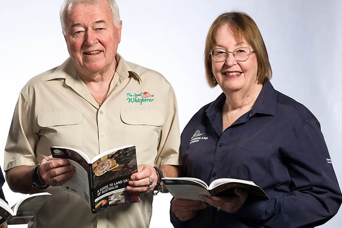 A man and woman smiling while holding a book each