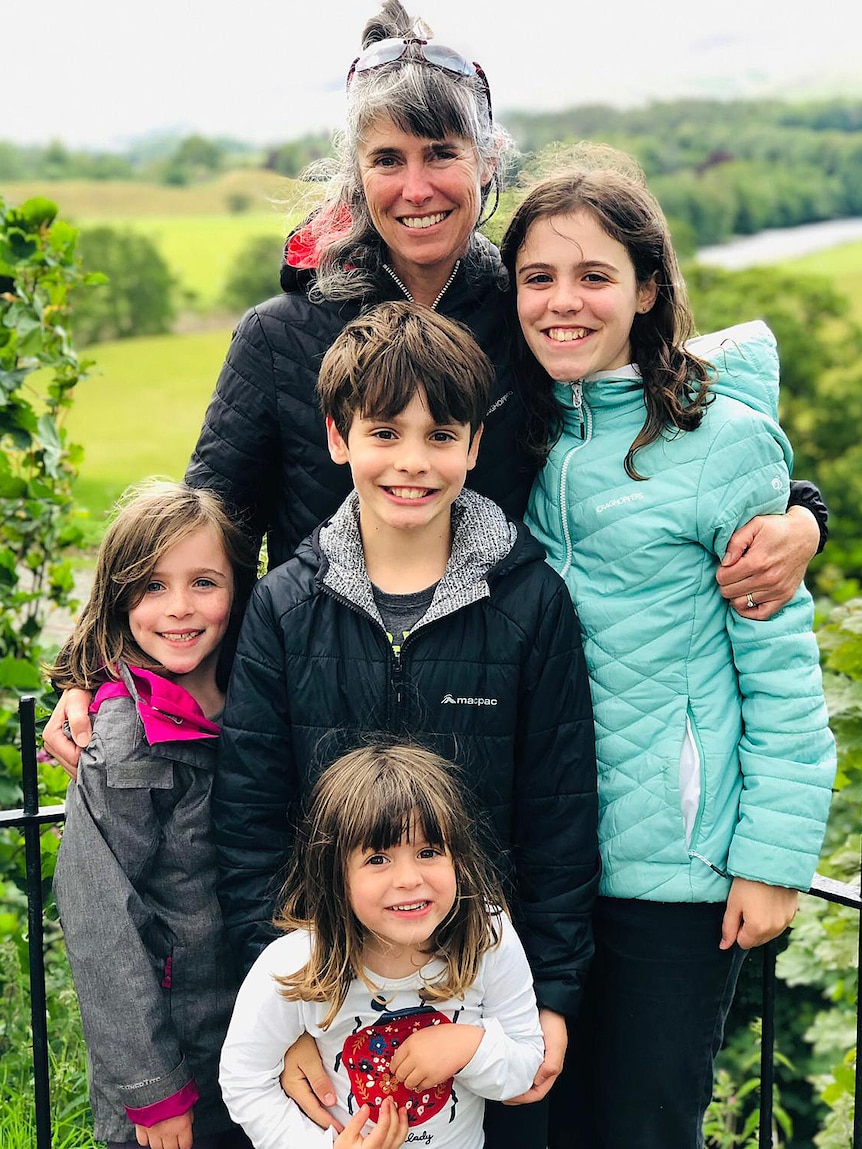 A woman and her four children stand outside.