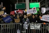 Protesters gather outside the JFK international terminal