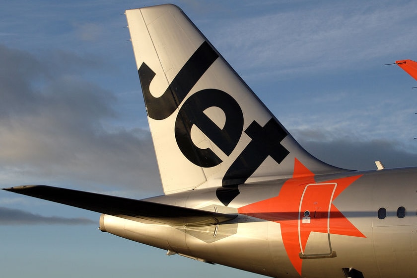 The tail of a Jetstar aircraft showing its name an livery.
