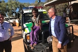 Jack Snelling and Jay Weatherill with a child on the bonnet of an SA ambulance.