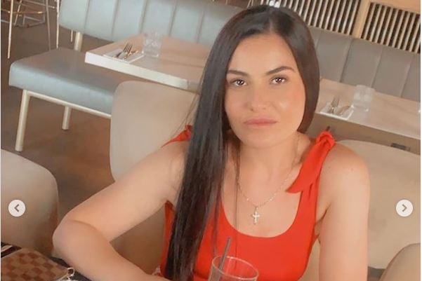 A woman wearing a red top sitting at a table in a cafe.