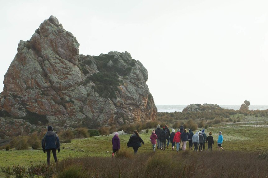 School group walks past huge coastal landmark, Church Rock