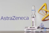 A AstraZeneca logo sits behind vials of generic vaccine.