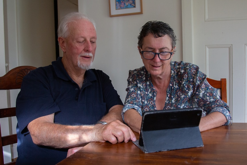 A man and a woman using a tablet.