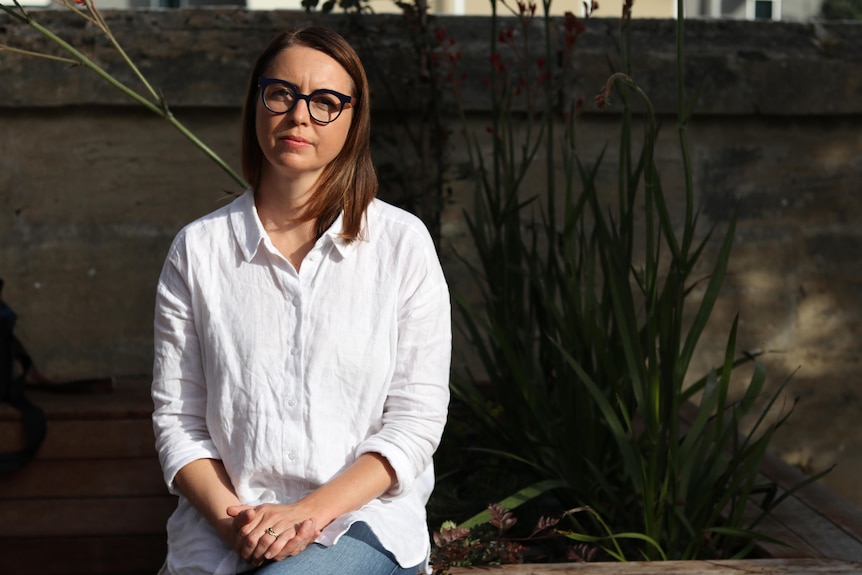 Portrait of a woman in white shirt with black rimmed glasses