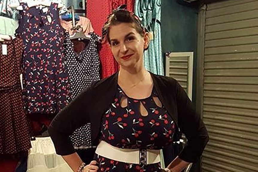 A woman poses for a photo in a clothing store.