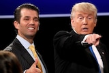 Donald Trump Jr smiles and gives a thumbs up while Donald Trump appears to point into the crowd.