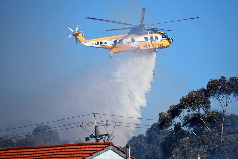 A helicopter dumps its load of water on a bushfire