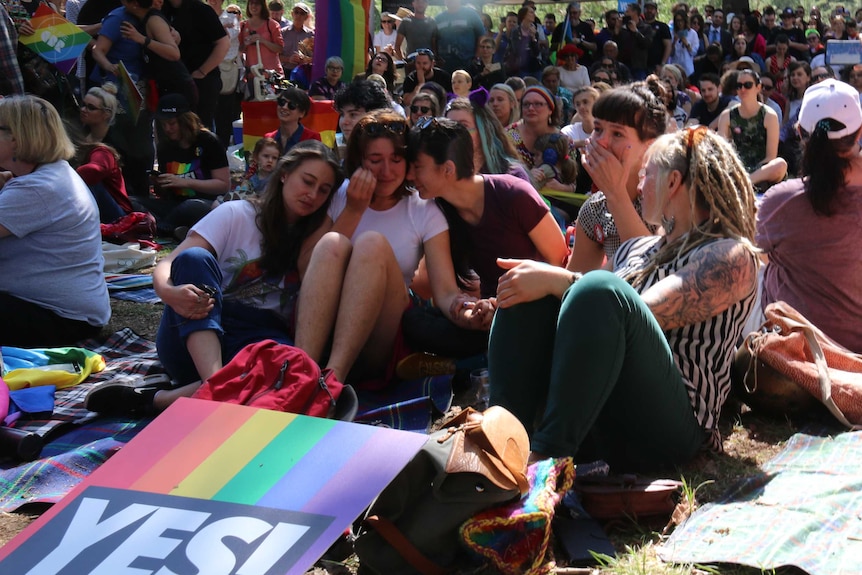 People are seen crying in a crowd in a Canberra park.
