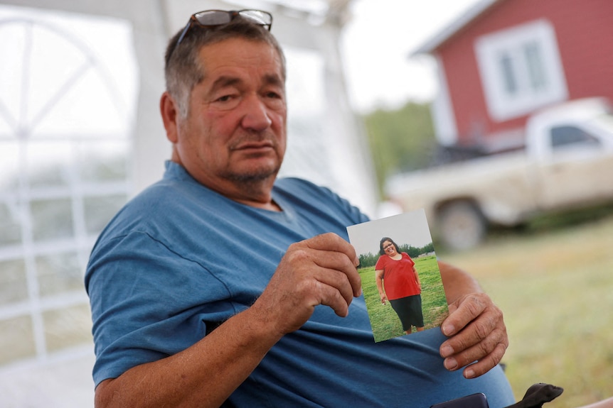 A man holds a photo of a woman