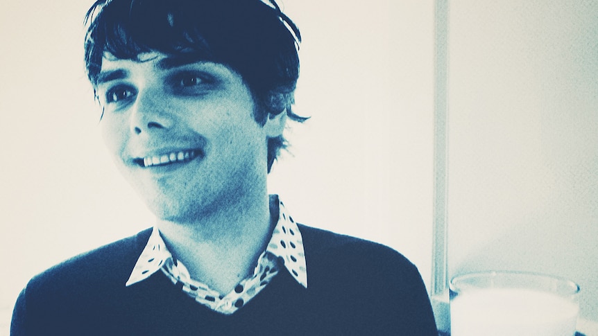 Grainy black and white photograph of musician Gerard Way wearing a sweater and smiling