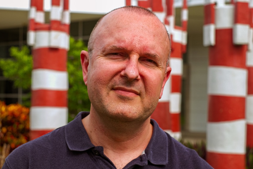 Headshot of bald man standing outside.