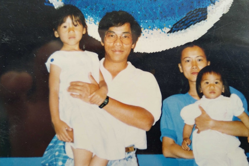 An old photo of a mother and father holding two daughters.