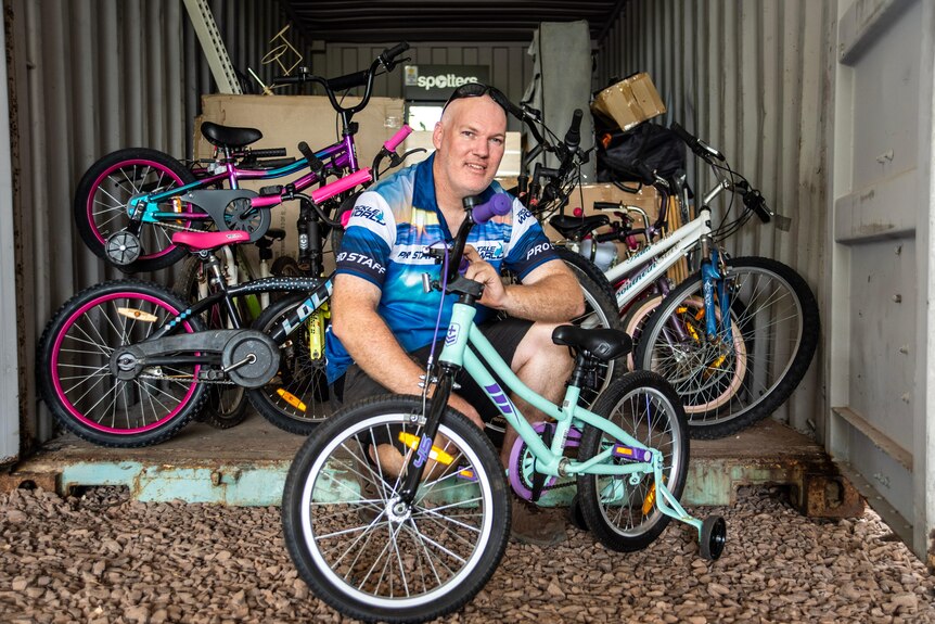 A man sits with some bikes. 