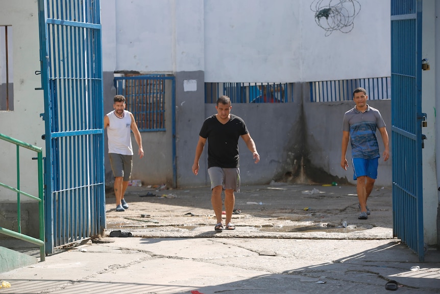 Three Colombian inmates walking around Haiti prison.