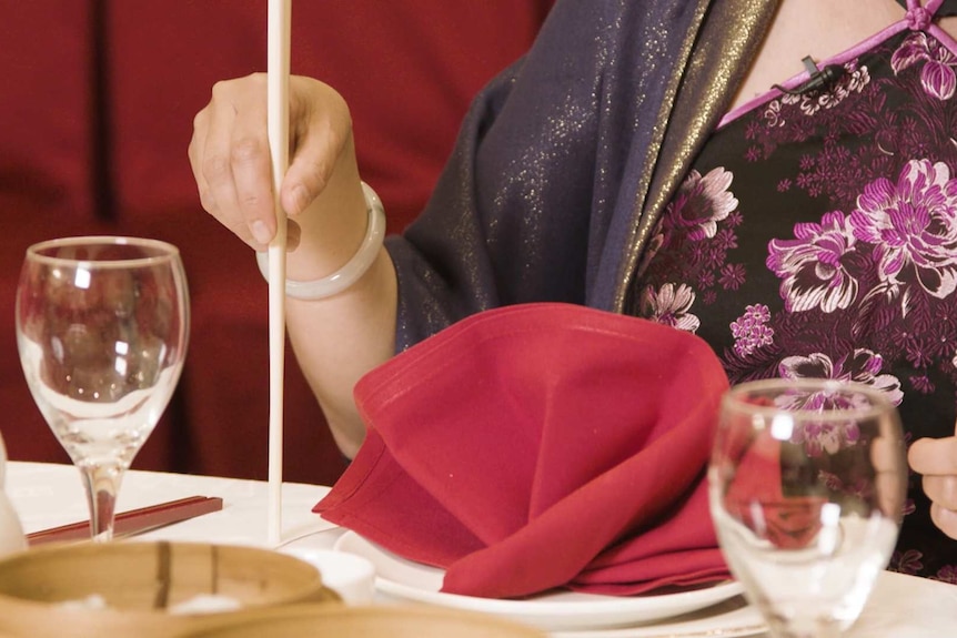 Close up of hand tapping chopsticks on the table
