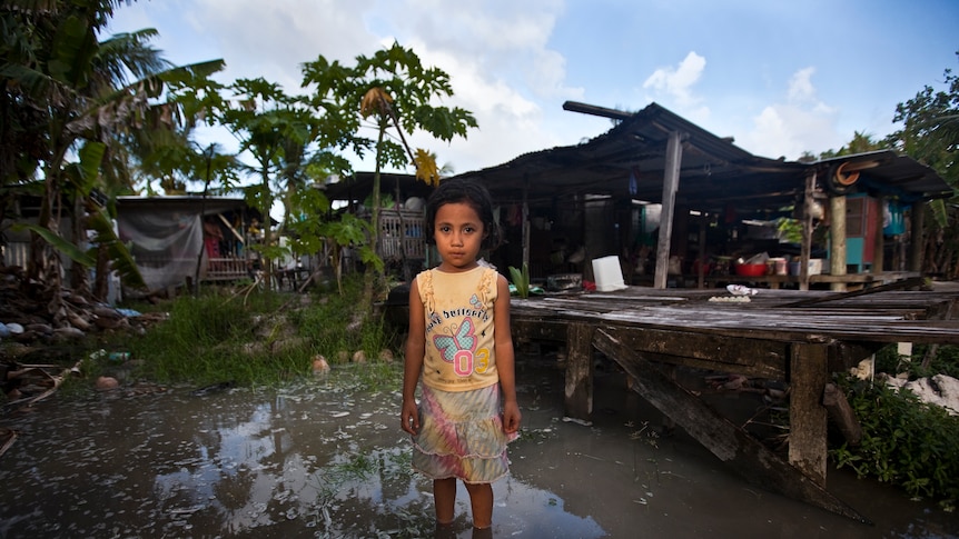 Teuga Patolo stands in king-tide waters that surround her neighbour's house at Funafui in Tuvalu.