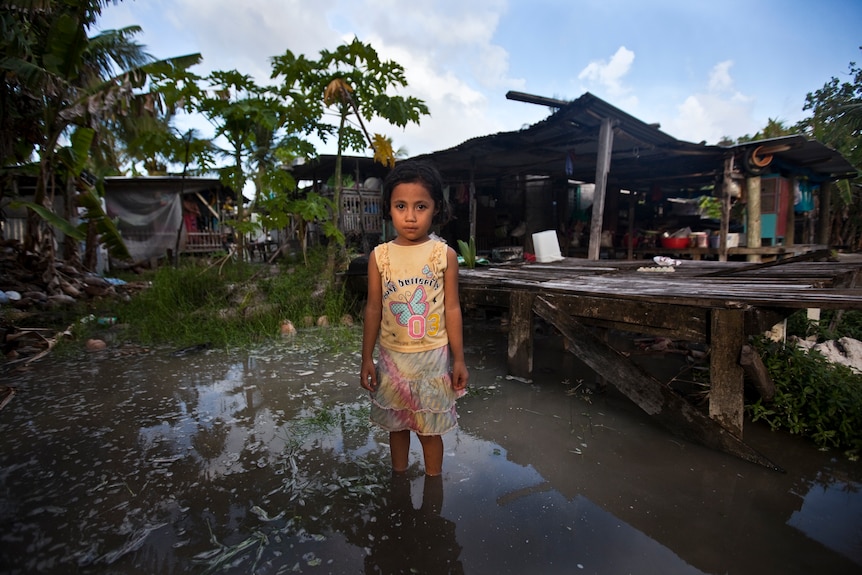 Teuga Patolo stands in king-tide waters that surround her neighbour's house at Funafui in Tuvalu.