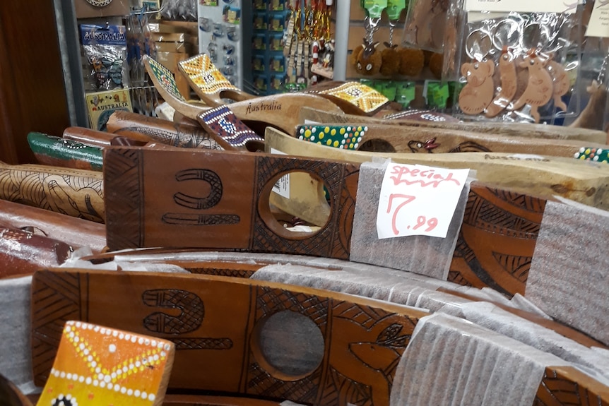 Wooden bottle holders and other souvenirs decorated in the style of Indigenous art.