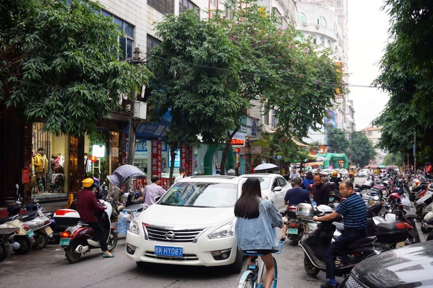 A street with several cars and motorcycles.