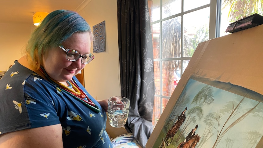 A woman wearing glasses paints a picture of horseriders