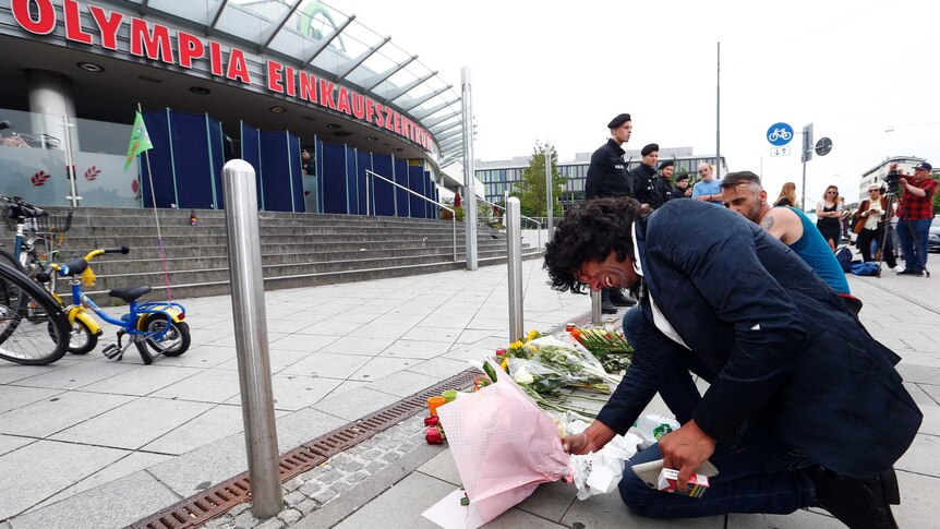 A crying man places flowers outside the Olympia shopping mall.