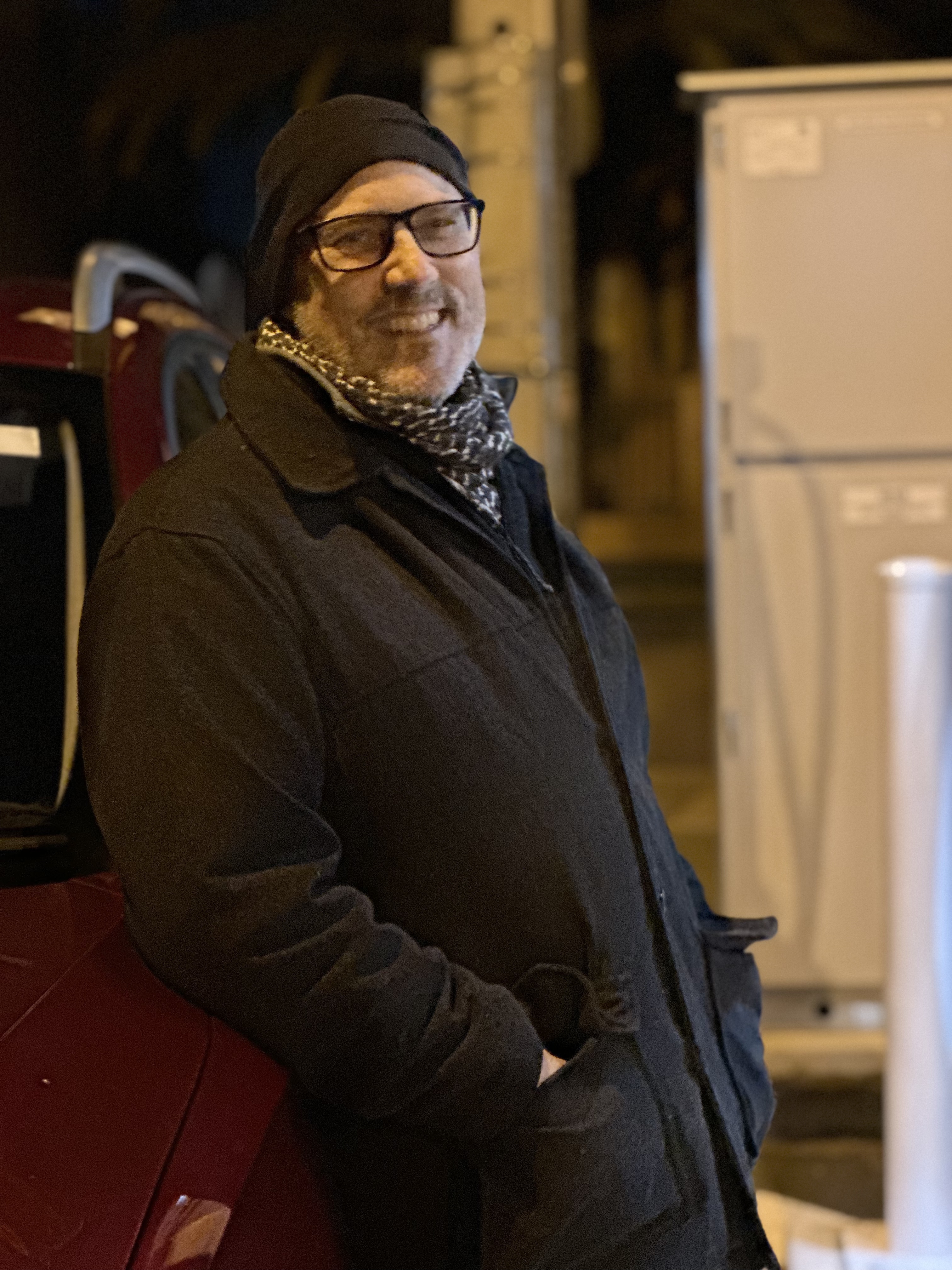 Michael Bond smiles, standing at an outdoor charging station.