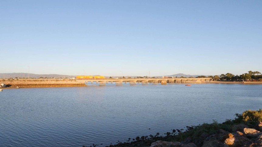 A picture of an estuary with a large bridge crossing over it, and traffic crossing.