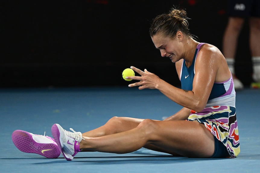 Aryna Sabalenka sits on the court after winning the Australian Open final.
