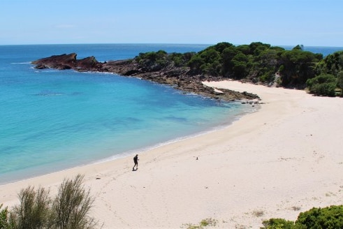 A lone hiker treks across the sand at Mowarry Beach.