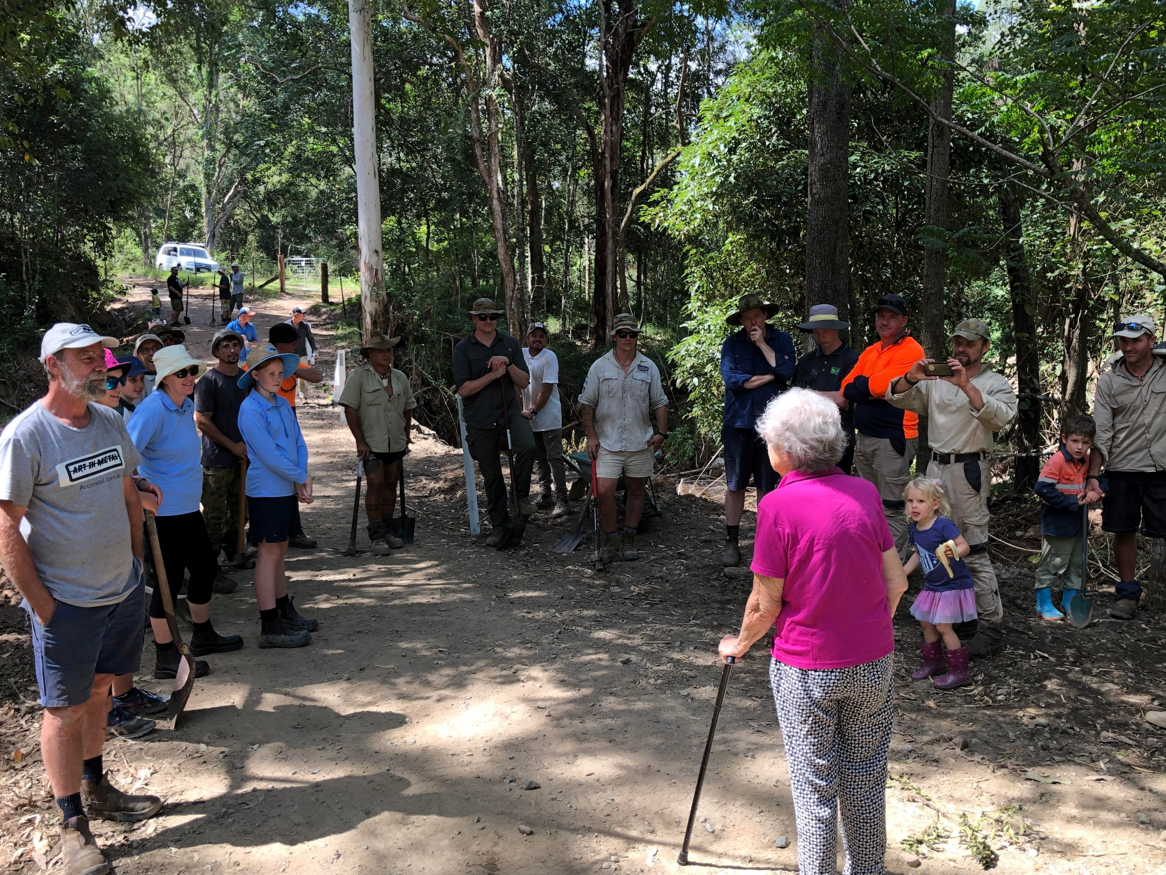 Woman with walking stick facing small group of people