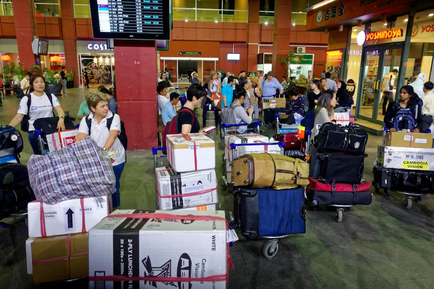 Boxes containing medical supplies are carried on luggage trolleys through a Cambodian airport.