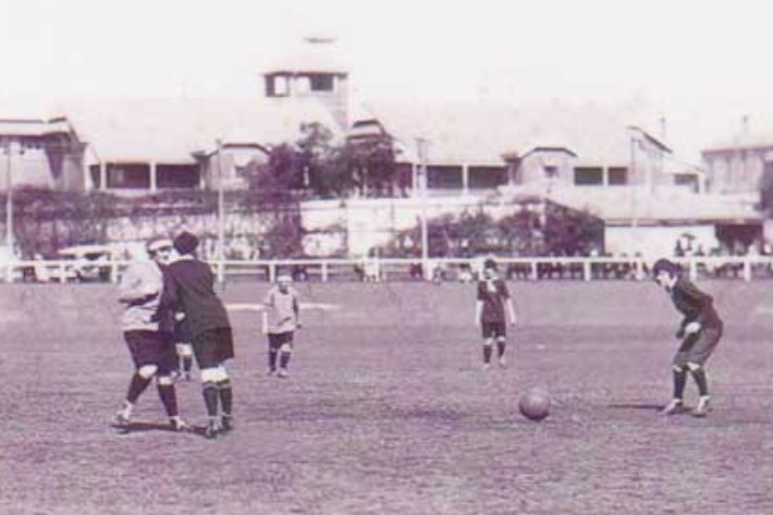 Women play football on a large open field in a black and white photo