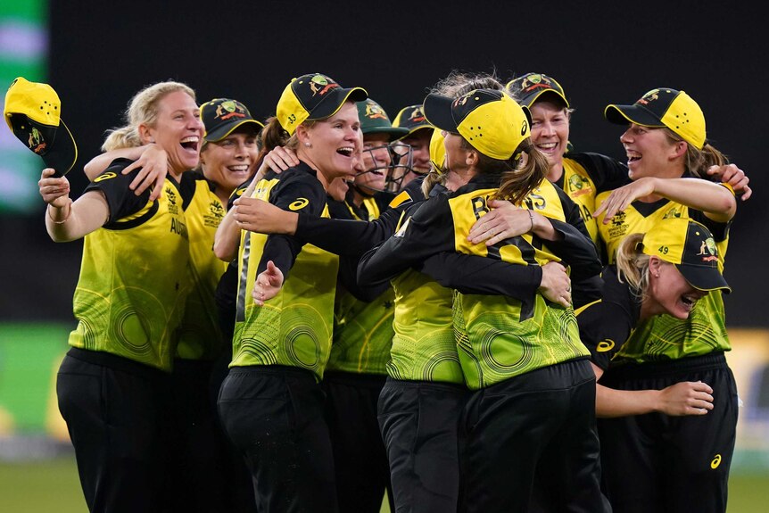 Australia's women's cricket team throw their arms around each other after the T20 World Cup final