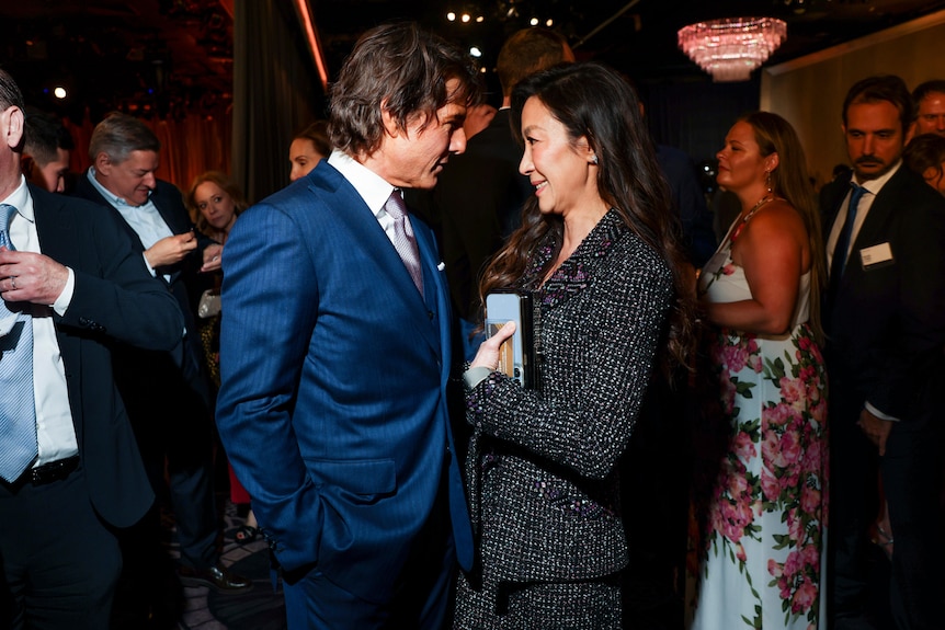 Tom Cruise leans in to talk to Michelle Yeoh. 