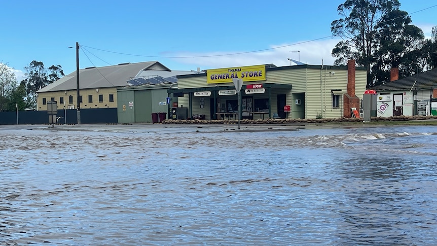 Tinamba general store in background with floodwaters in front covering the road