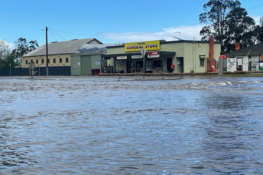 Tinamba general store in background with floodwaters in front covering the road