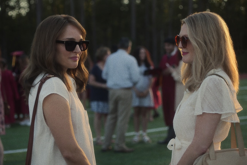 A film still of Natalie Portman and Julianne Moore, each wearing sunglasses. Moore smiles looking at Portman, who looks away.