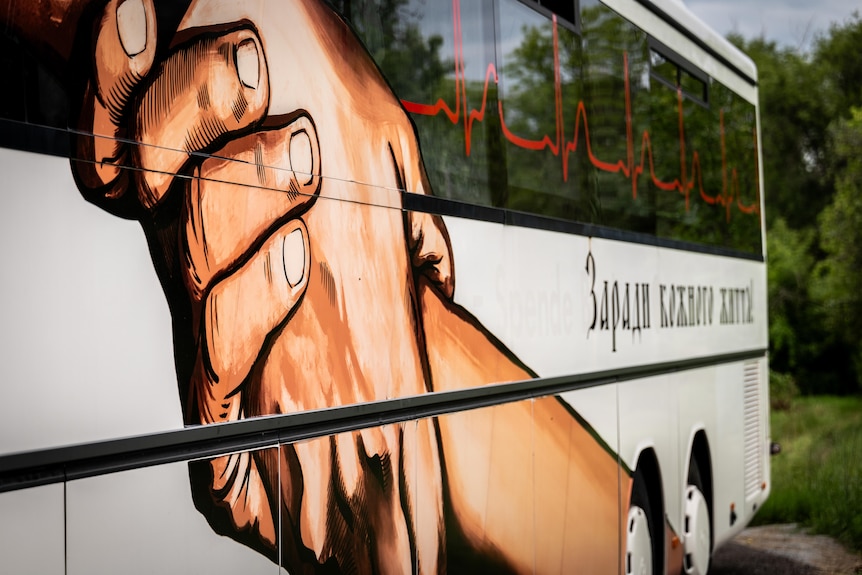 An illustration of two hands holding each other painted on the outside of a white bus