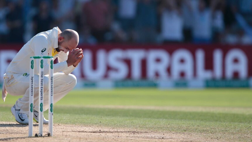 Nathan Lyon crouches down on his haunches next to the stumps