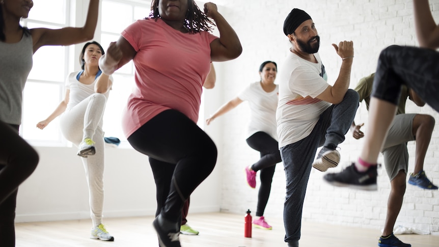 A group of people exercise in a class.