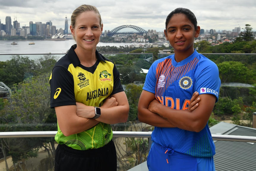 Two female cricketers stand with their arms folded, with Sydney Harbour in the background.