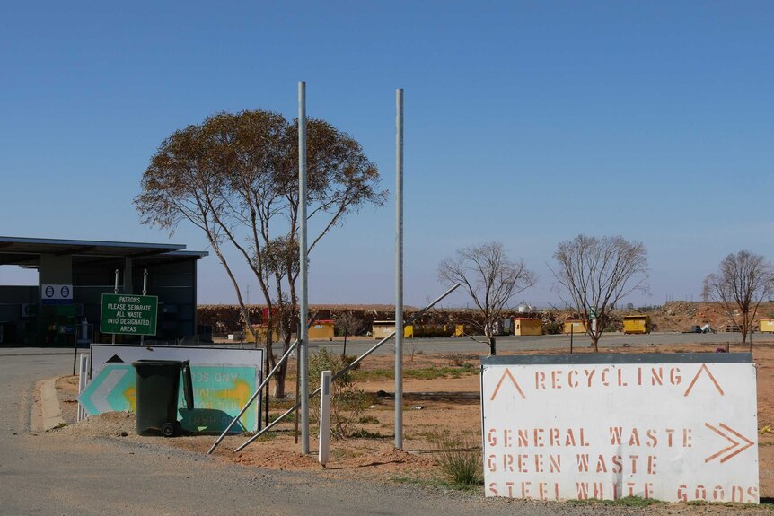Long shot of the tip of Broken Hill with a sign pointing to 'Recycling', 'Steel white goods', 'General' and 'Green' waste